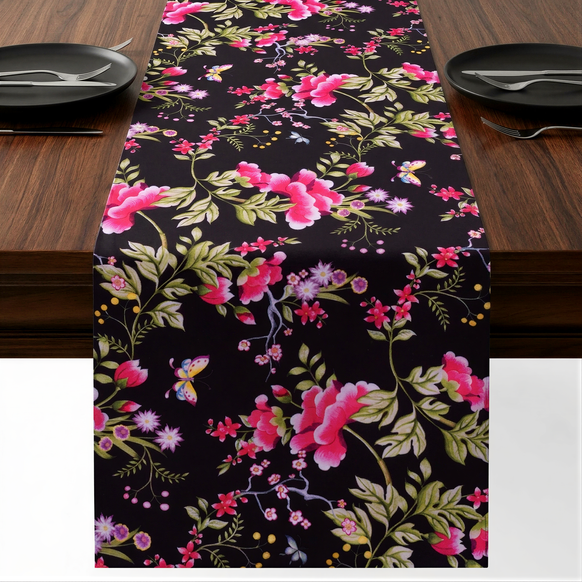 a table runner with a floral pattern in shades of pink and green, placed on a wooden table. The runner is adorned with small pink flowers and green leaves, creating a visually appealing and decorative touch to the table setting.