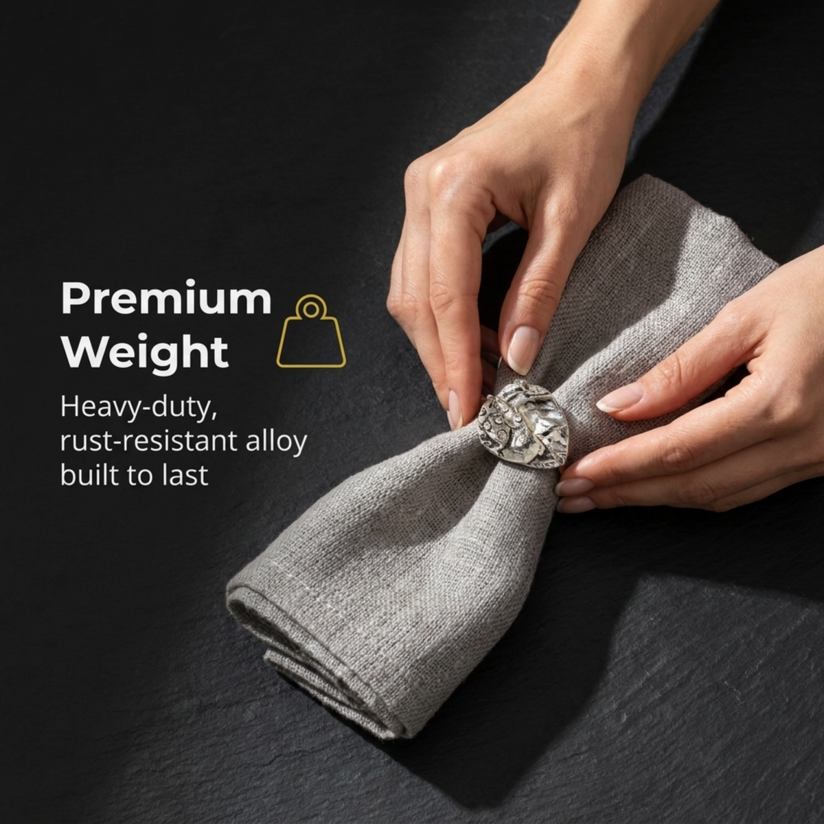 A pair of hands holding a gray napkin with a decorative metal piece on it, and text above the image stating "Premium Weight" and "Heavy-duty, rust-resistant alloy built to last".