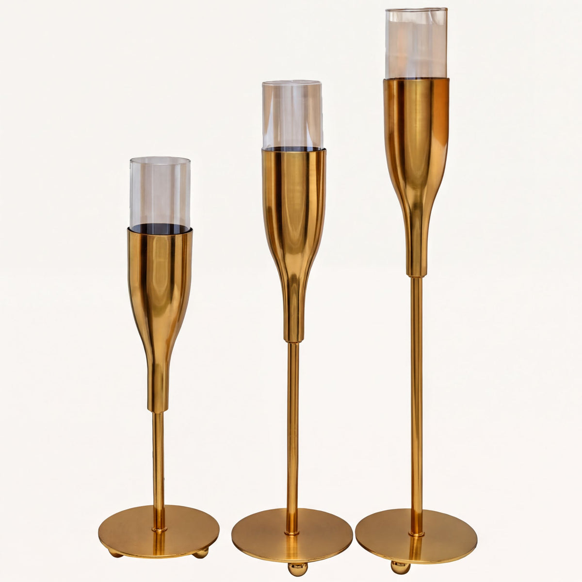 Set of three gold wine glass-shaped candle holders, elegant decorative accessories for tabletop or mantel displays.