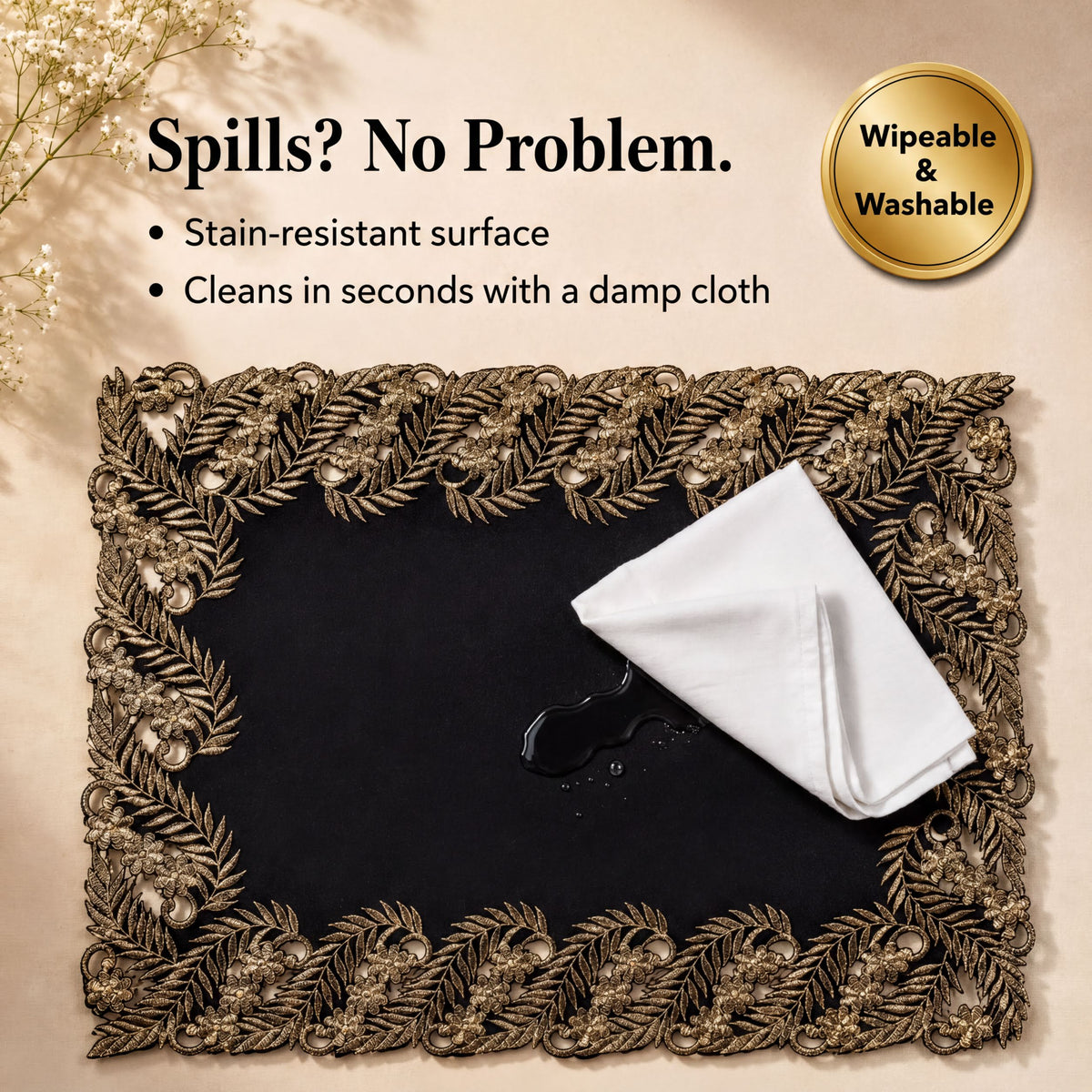 a decorative placemat with a gold leaf frame, placed on a black surface. A white cloth is placed on the placemat, and there is a small amount of liquid on the cloth, possibly from a spill. The image includes text that describes the placemat as stain-resistant, durable, and easy to clean, and it is described as "Wipeable & Washable".