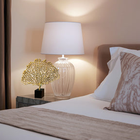 a well-lit bedroom corner with a bed, a lamp, and a decorative piece on a side table.