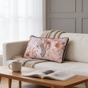 a cozy living room with a white sofa, a wooden coffee table, and a decorative pillow with a floral design. There is also a mug and an open book on the coffee table, creating a comfortable and inviting atmosphere.