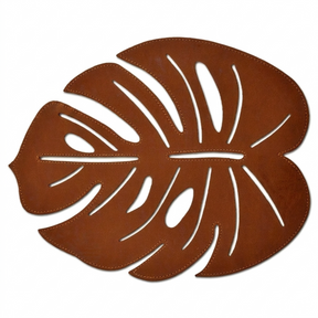 Set of six Monstera leaf cut out leather placemats in brown, showcasing detailed tropical leaf design for stylish table setting.