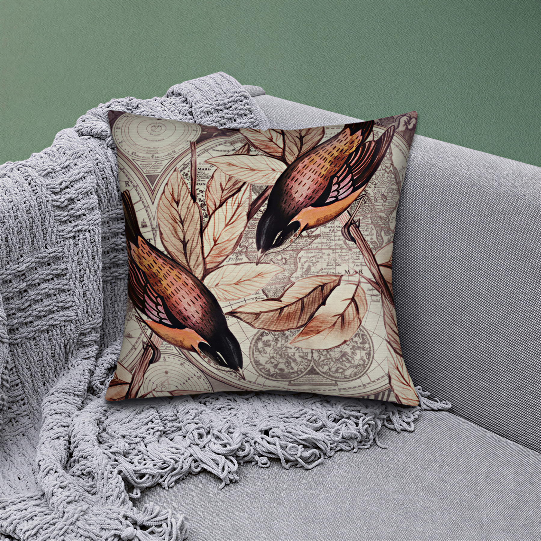 A decorative throw pillow with a bird design sits on a gray couch, partially covered by a gray blanket.