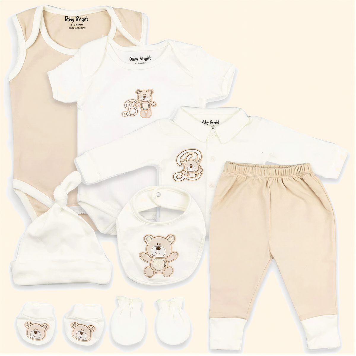 A collection of baby clothing and accessories, including a onesie, a shirt, pants, a hat, a bib, and mittens, all featuring a teddy bear design.