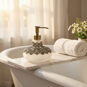 A white marble bathtub with a decorative soap dispenser, a rolled white towel, and a vase of white flowers on the edge.