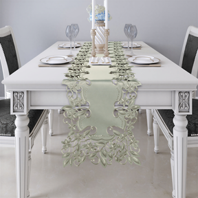 a white dining table set with a floral table runner, plates, and wine glasses.