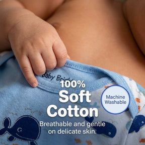 A close-up image of a baby's hand and arm wearing a blue baby onesie, with text highlighting the 100% soft cotton material and machine washable quality.