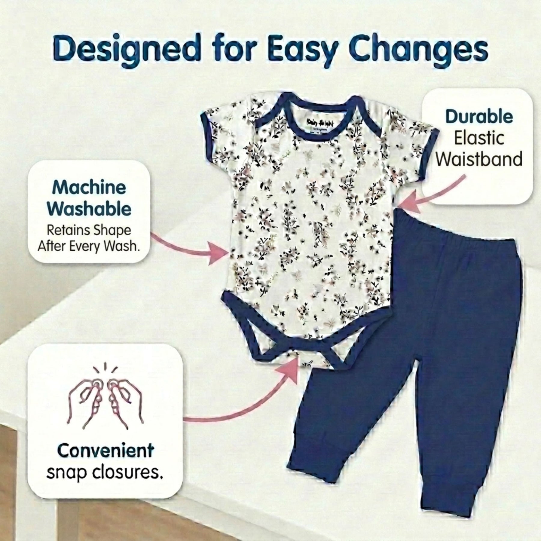 The image is a product advertisement for baby clothing, specifically a white onesie with a floral pattern and blue pants. The ad highlights the convenience of the product, such as the machine washable waistband and the elastic waistband, which are designed for easy changes.