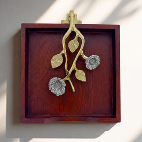 A wooden tray with a decorative metal piece featuring a branch with flowers on it.