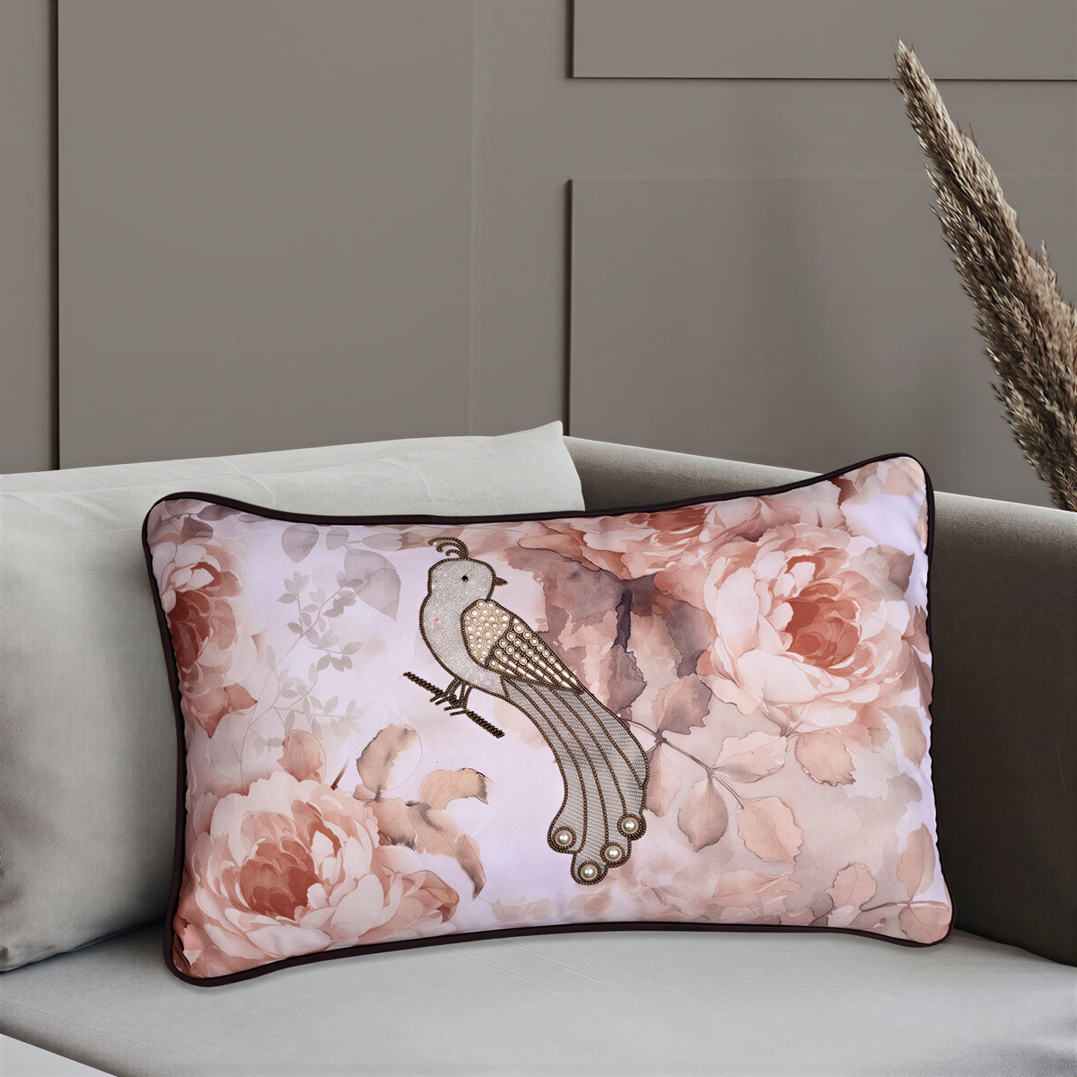 A decorative pillow with a floral pattern and a bird design sits on a couch.
