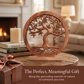 a wooden tree-shaped ornament on a wooden table, with a stack of books and a gift box nearby. The scene is set in a cozy living room with a fireplace visible in the background.