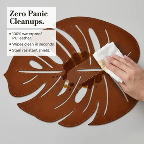 Set of six Monstera leaf cut out leather placemats in brown, featuring tropical leaf design, perfect for dining table decor.