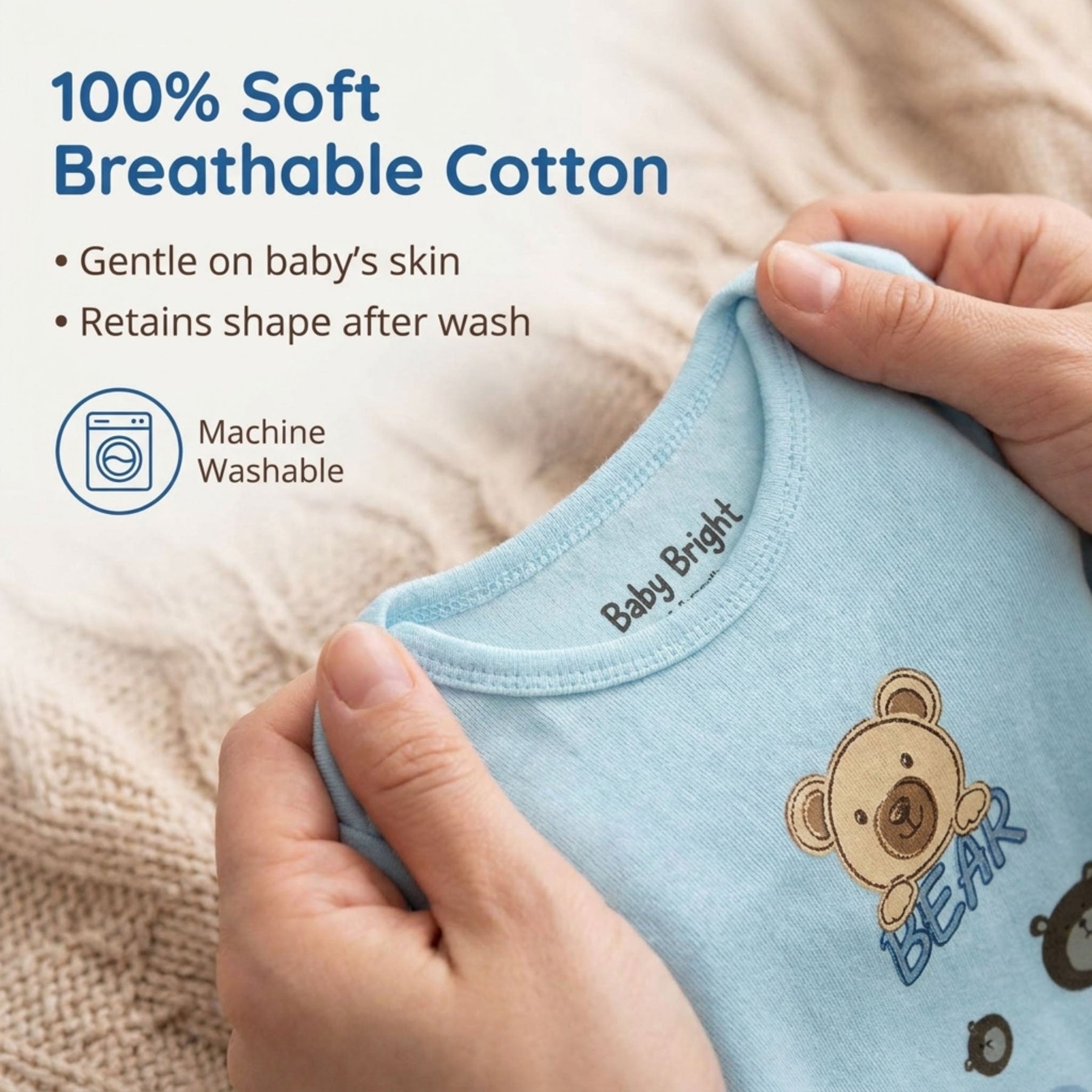A pair of hands holding a light blue baby onesie with a teddy bear design.
