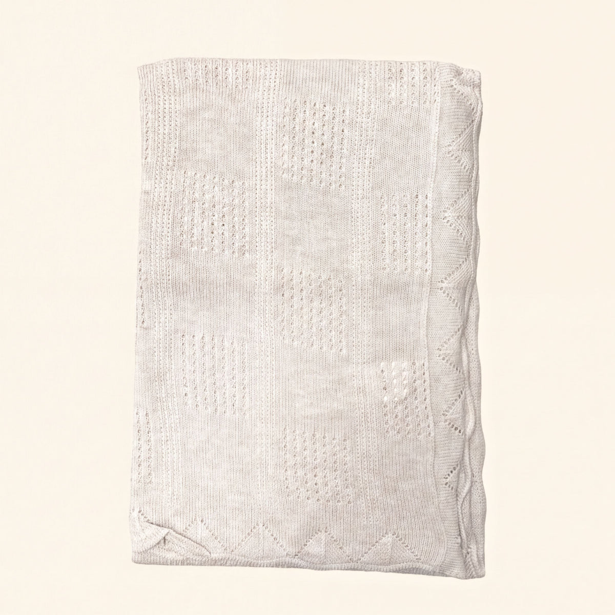A cream-colored knitted blanket with a geometric pattern.