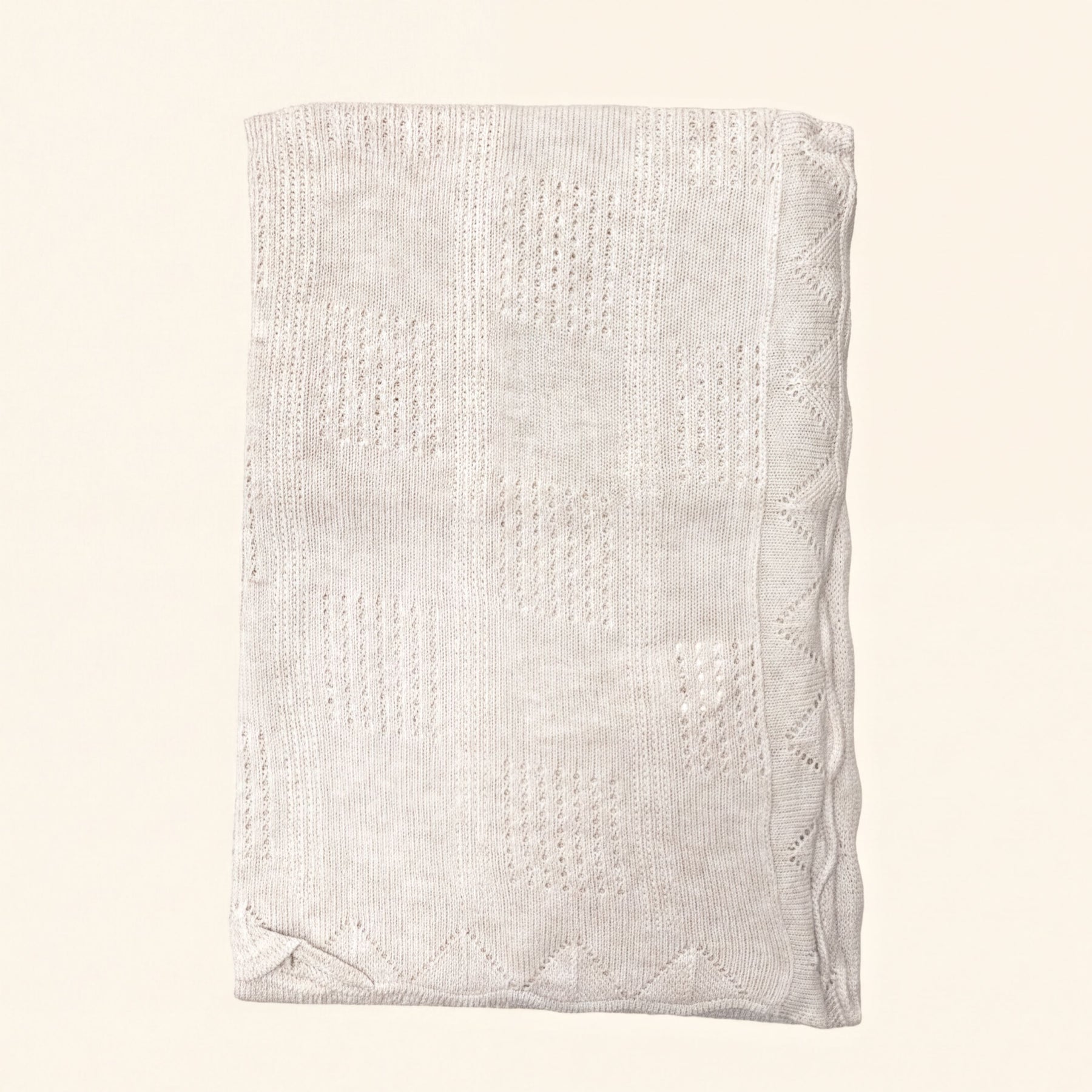 A cream-colored knitted blanket with a geometric pattern.
