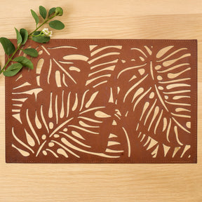 Set of six Monstera leaf cut out leather placemats by ACM1247-BRN, featuring tropical leaf design for stylish table setting.
