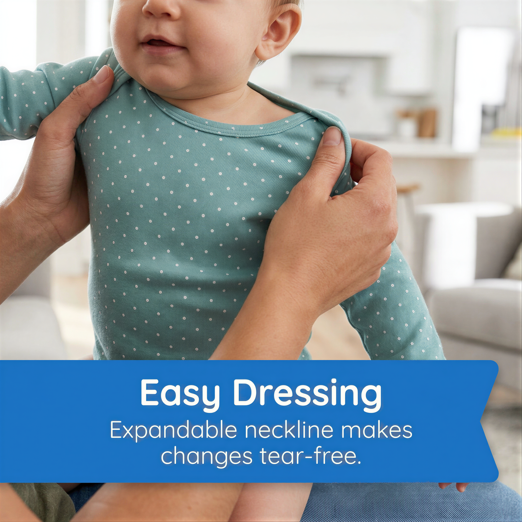 A baby wearing a green polka dot shirt is being held by someone's arms, with a caption below the image stating that an expandable neckline makes dressing tear-free.