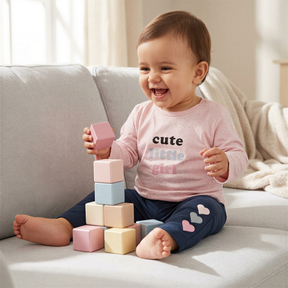 A smiling baby girl sitting on a couch and playing with colorful blocks.