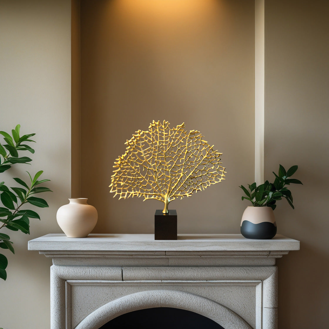 a white fireplace mantel with a decorative gold leaf sculpture and two small vases placed on it.