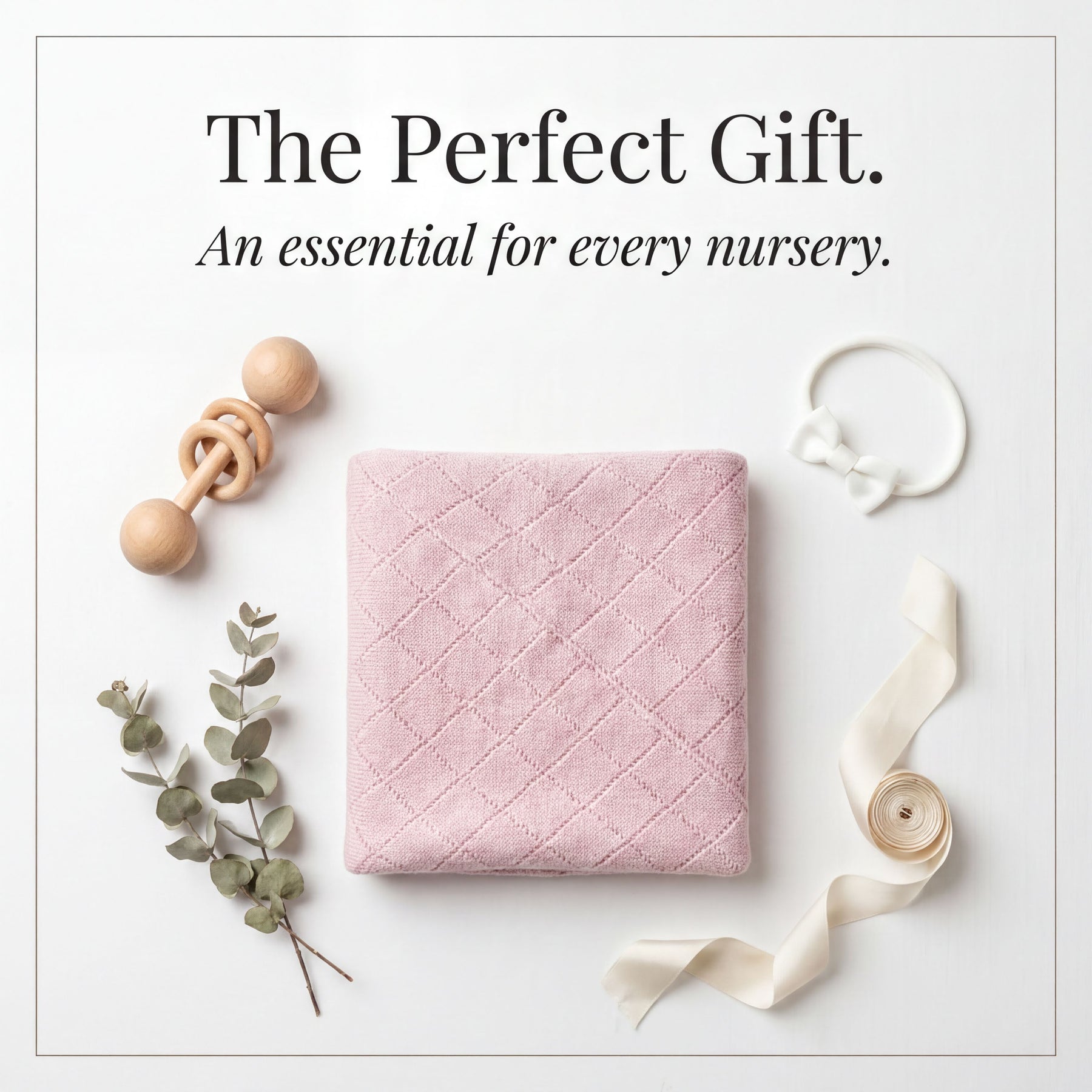 a collection of baby-related items arranged on a white background, including a pink quilted blanket, a wooden baby rattle, a white bow, and some greenery.