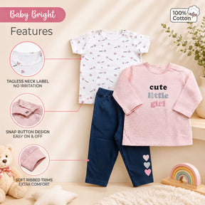 a baby outfit set, including a white t-shirt with a patterned design, a pink long-sleeved shirt with the text "cute little girl", and blue pants with three hearts on the side. The outfit appears to be made of 100% cotton, and there are various features described, such as a tagless neck label, snap button design, soft ribbed trims, and extra comfort.