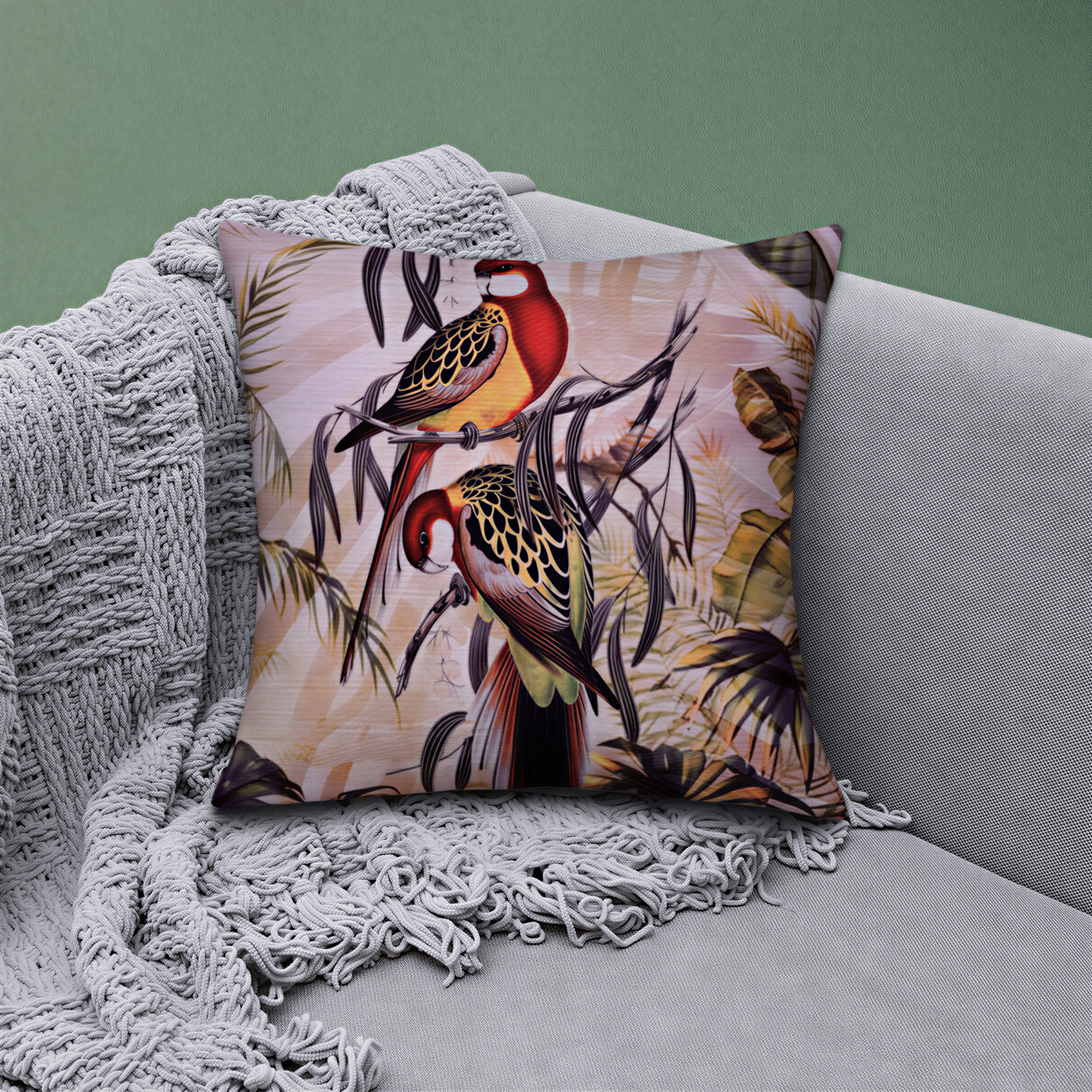A decorative throw pillow with a vibrant, colorful bird design is placed on a gray couch, with a gray blanket draped over the arm of the couch.