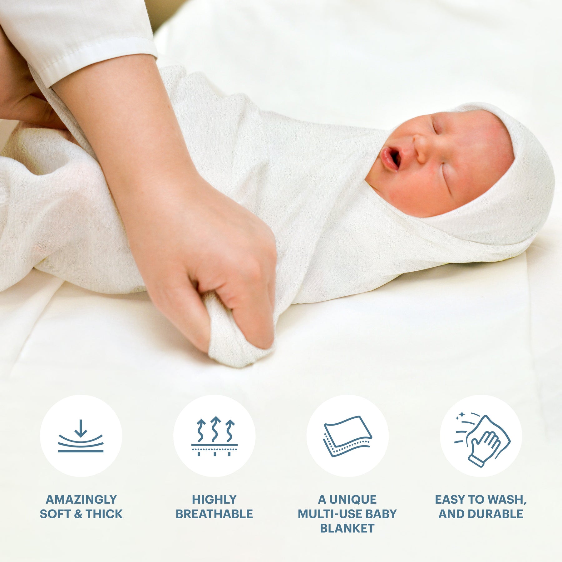 a person wrapping a baby in a soft and thick white blanket.