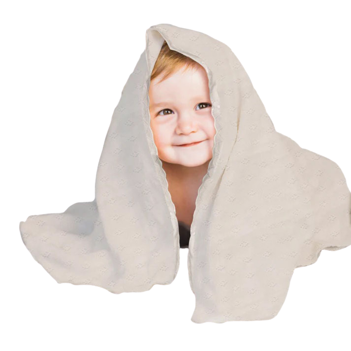 A young child with a smile on their face is partially hidden behind a white, patterned blanket.