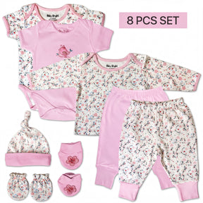 A set of baby clothing items, including a pink onesie, pants, a hat, and booties, arranged on a white background.