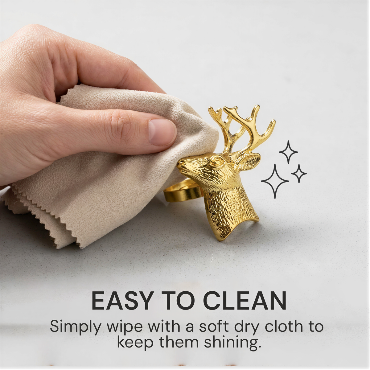 A hand is cleaning a gold-colored deer head ring with a soft dry cloth, as indicated by the text "EASY TO CLEAN Simply wipe with a soft dry cloth to keep them shining."