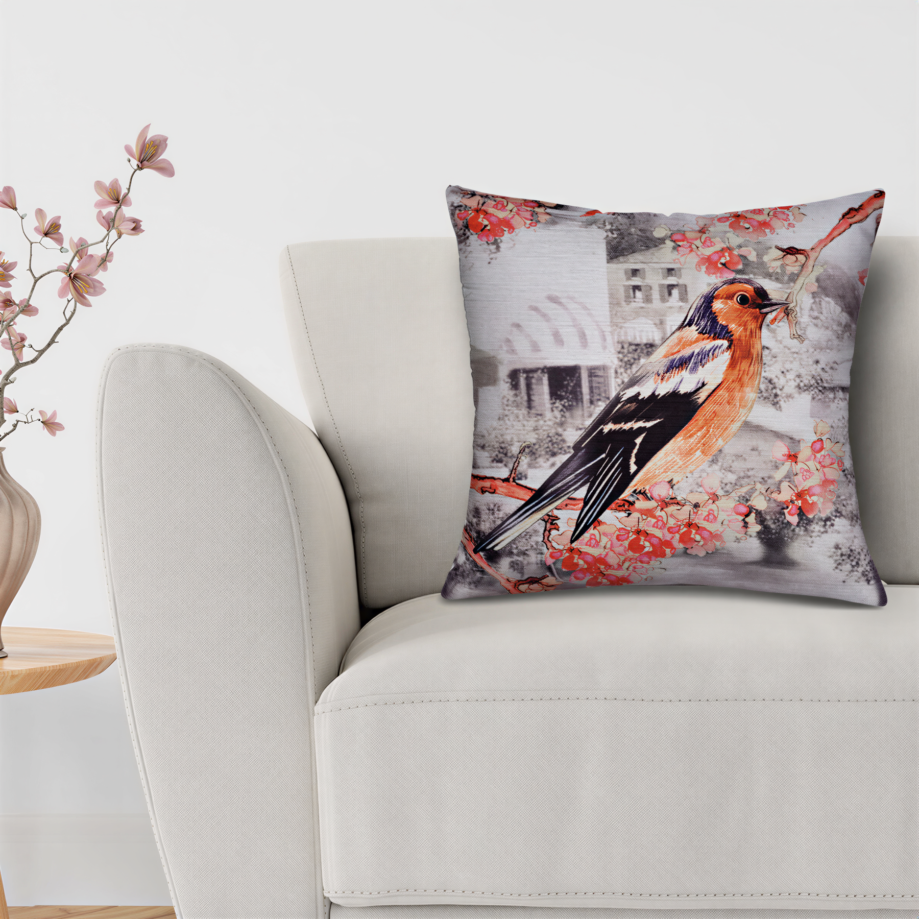 A white sofa with a decorative throw pillow featuring a colorful bird image.