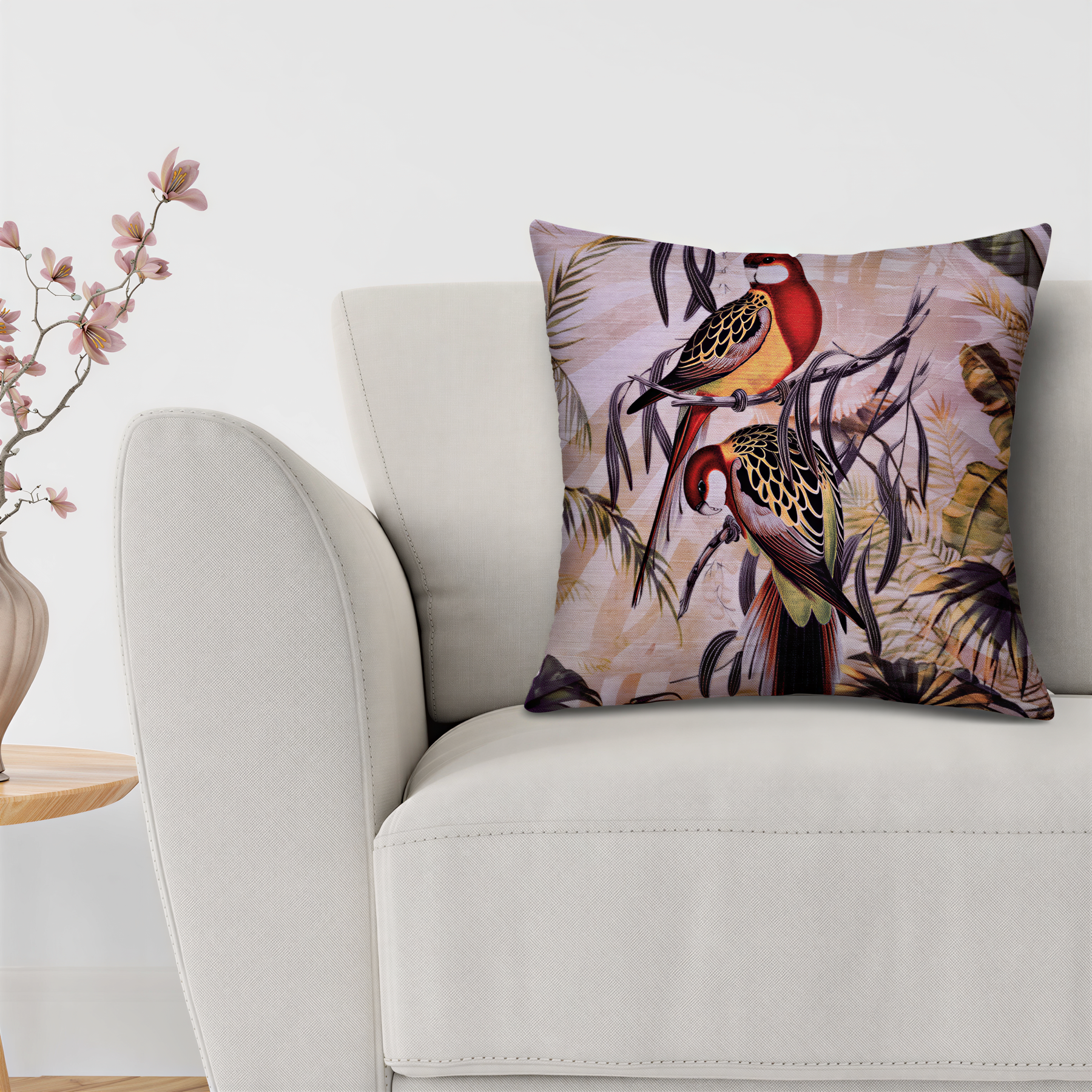 A white sofa with a decorative throw pillow featuring a colorful illustration of two birds perched on branches.