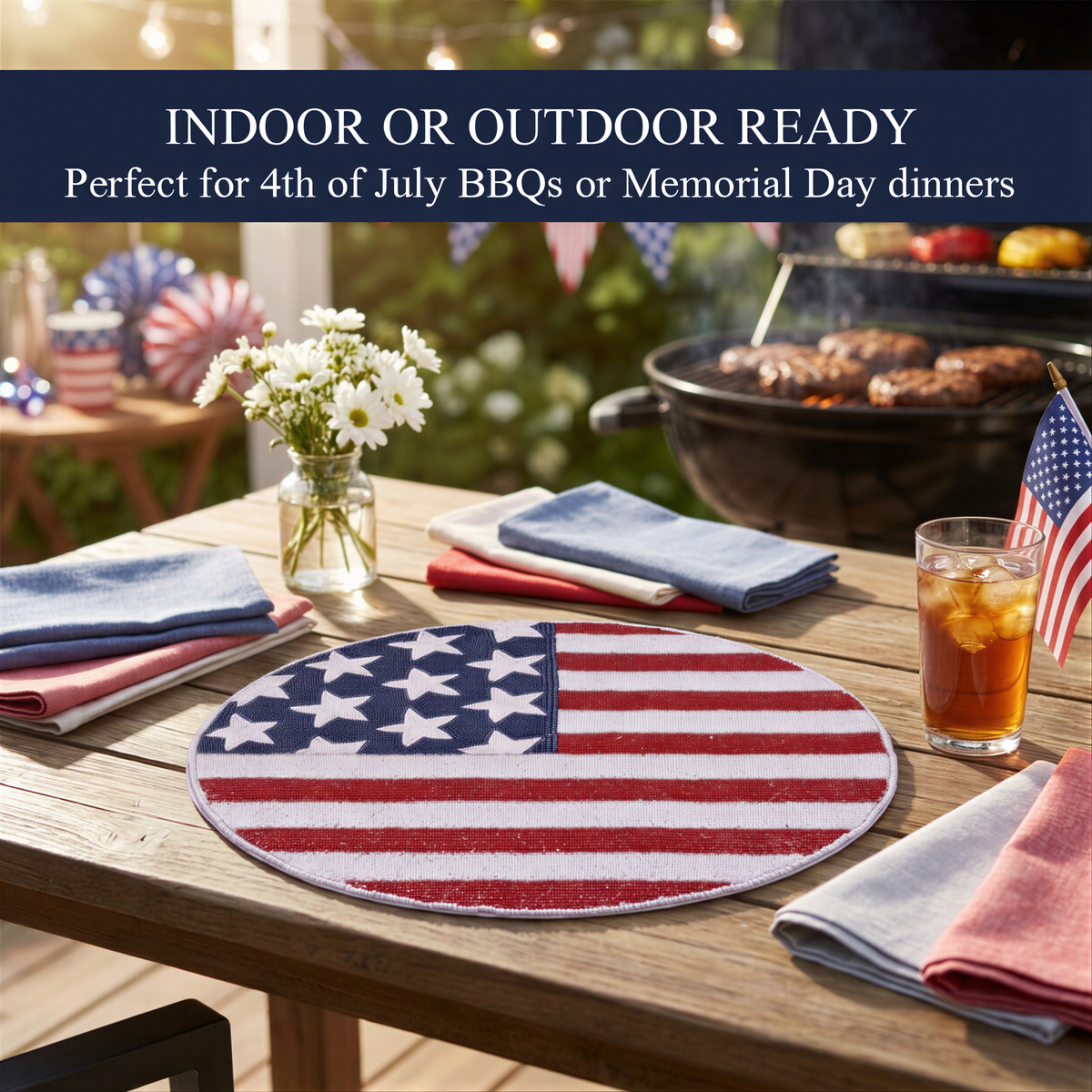 a patriotic table setting with an American flag-themed place mat, a vase of white flowers, and a glass of iced tea. The table is set for an outdoor BBQ or Memorial Day dinner, with a grill visible in the background.