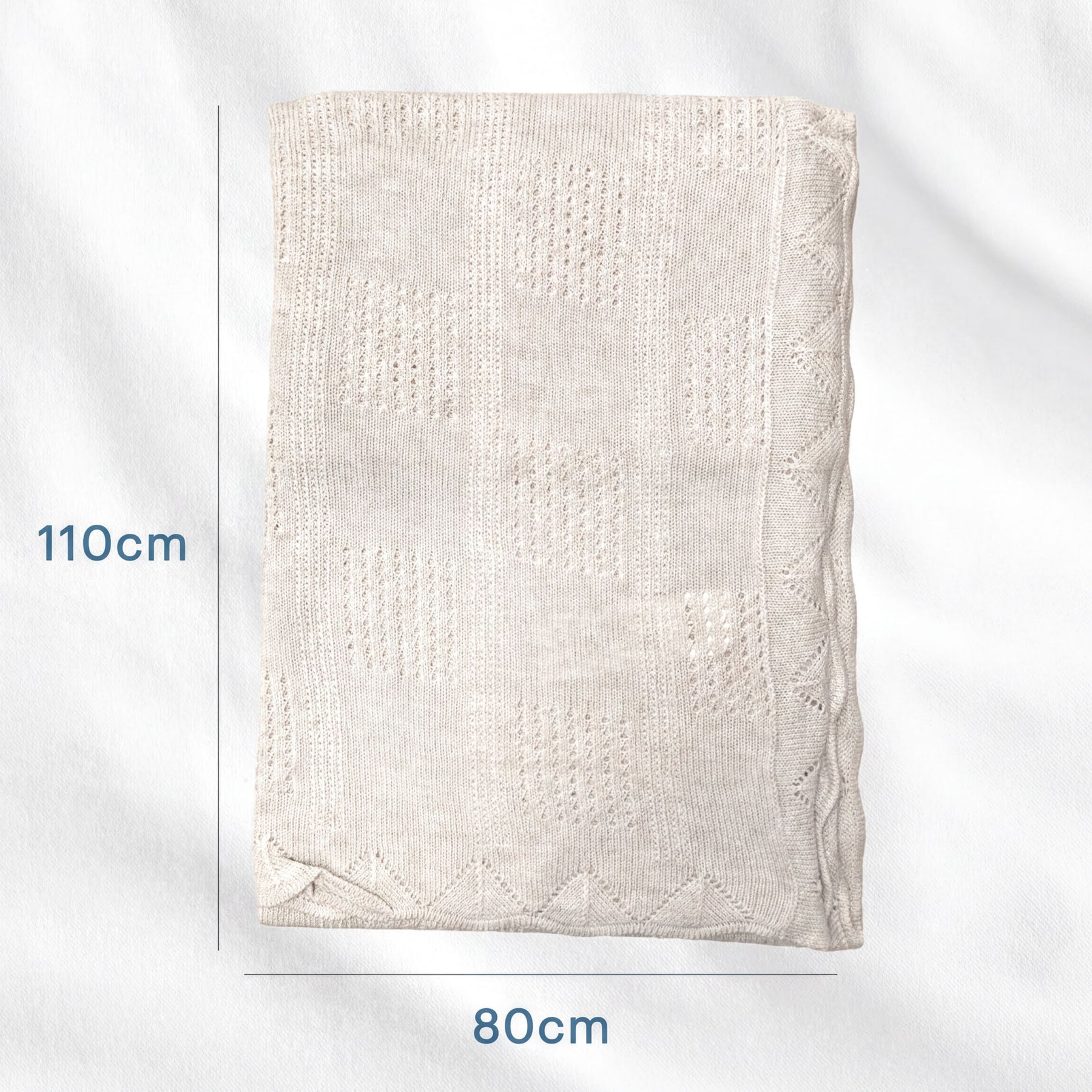 a light-colored blanket or quilt with a geometric pattern, placed on a white background.