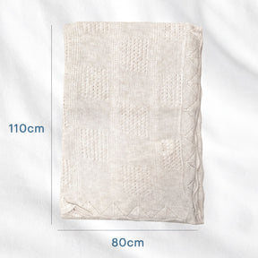 a light-colored blanket or quilt with a geometric pattern, placed on a white background.