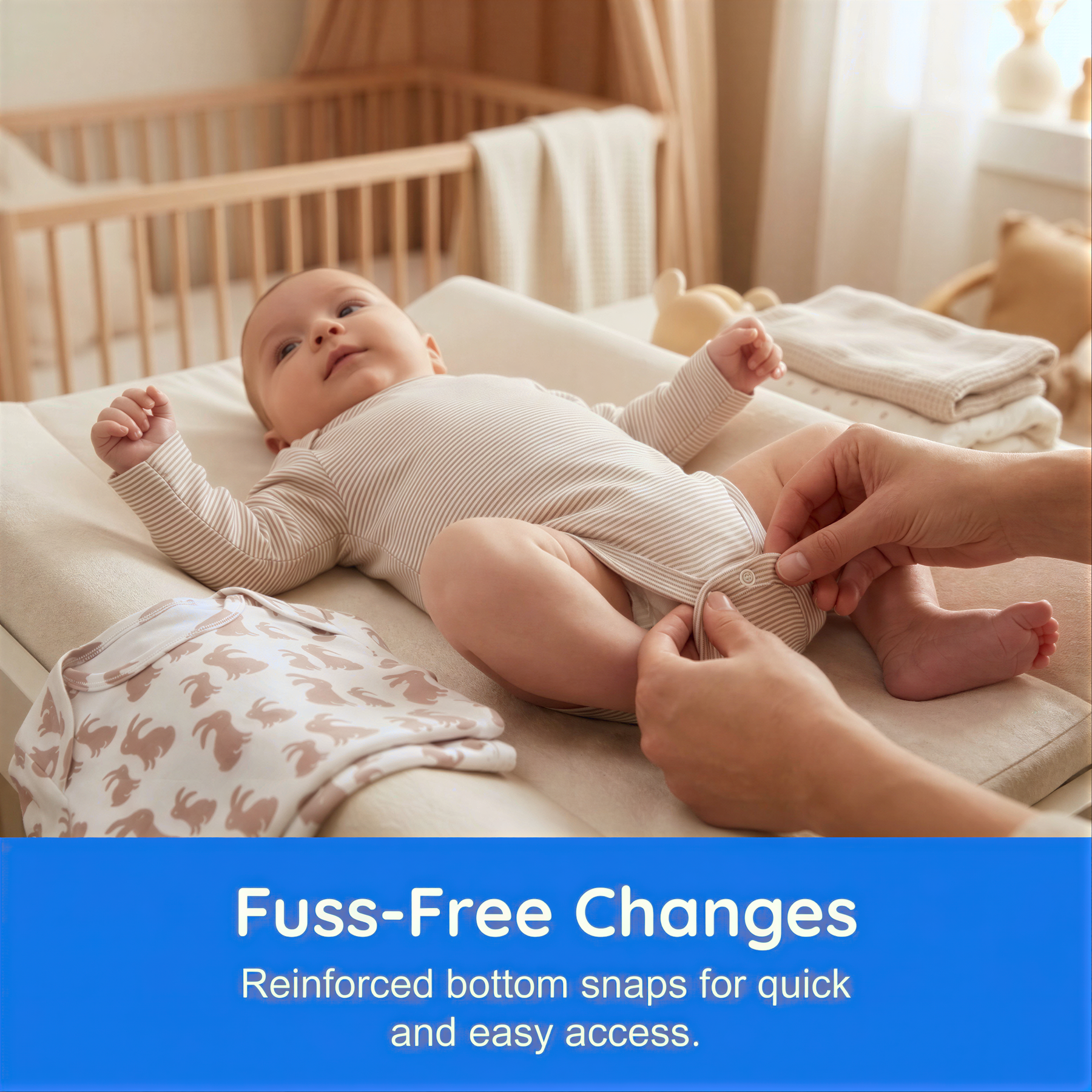 A baby lying on a changing pad, with a person's hands adjusting the baby's clothing.