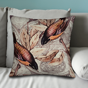 A decorative throw pillow with a bird and leaf pattern on it, placed on a couch.