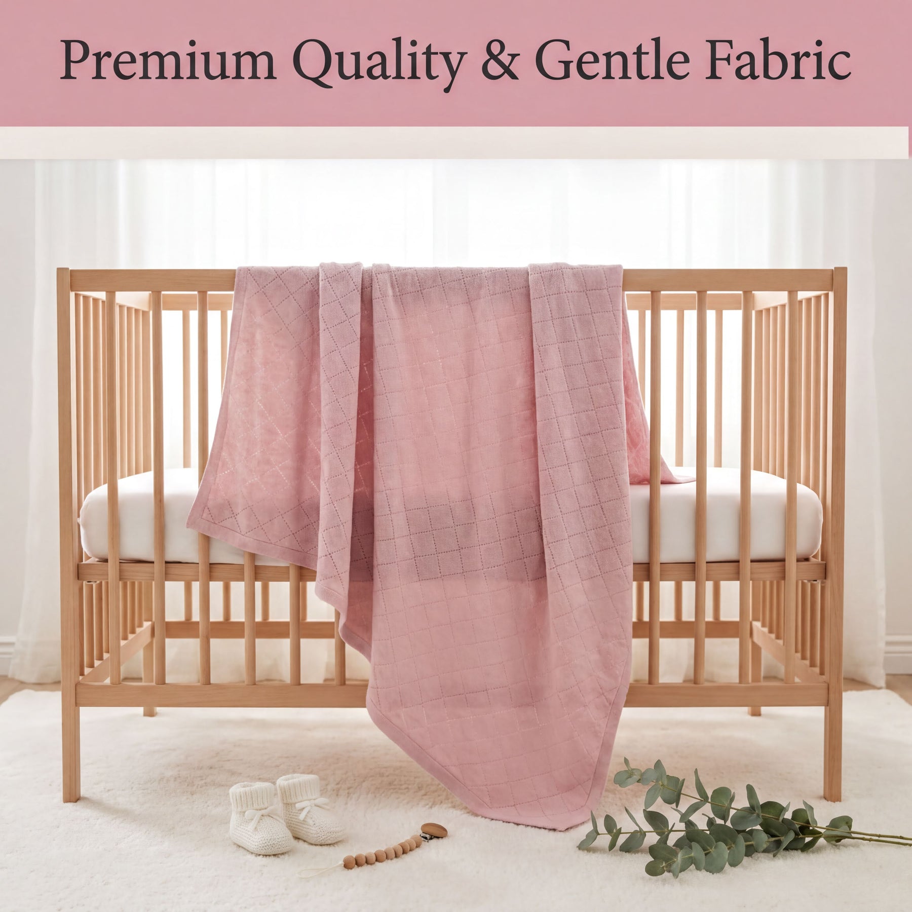A wooden crib with a pink blanket draped over it, along with a pair of white baby shoes and a small plant on the floor.