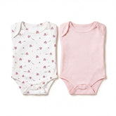 two baby onesies, one white with a pattern of hearts and one pink with polka dots, both laid out on a white background.