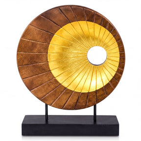 a circular sculpture with a golden and brown color scheme, placed on a black stand.