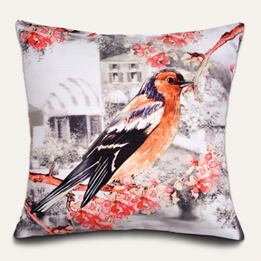 A decorative pillow with a colorful illustration of a bird perched on a branch with flowers.