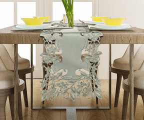 a dining table with a decorative table runner, yellow bowls, and a vase of green plants.
