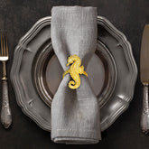 Set of four Ocean Majesty gold napkin rings featuring elegant sea horse designs, perfect for decorative dining table accents.