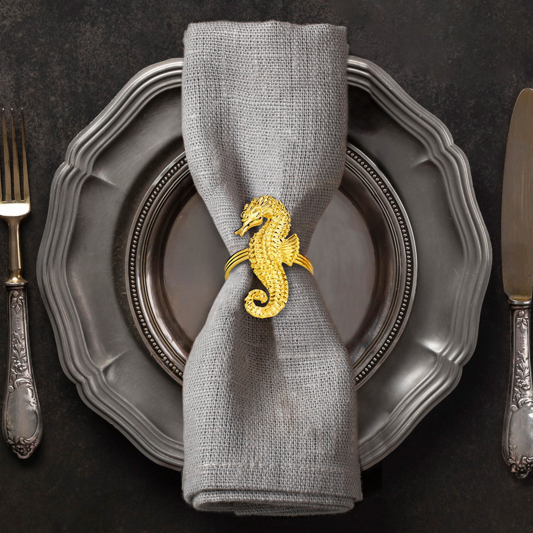 Set of four Ocean Majesty gold napkin rings featuring elegant sea horse designs, perfect for decorative dining table accents.