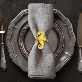 Set of four Ocean Majesty gold napkin rings featuring elegant sea horse designs, perfect for decorative dining table accents.